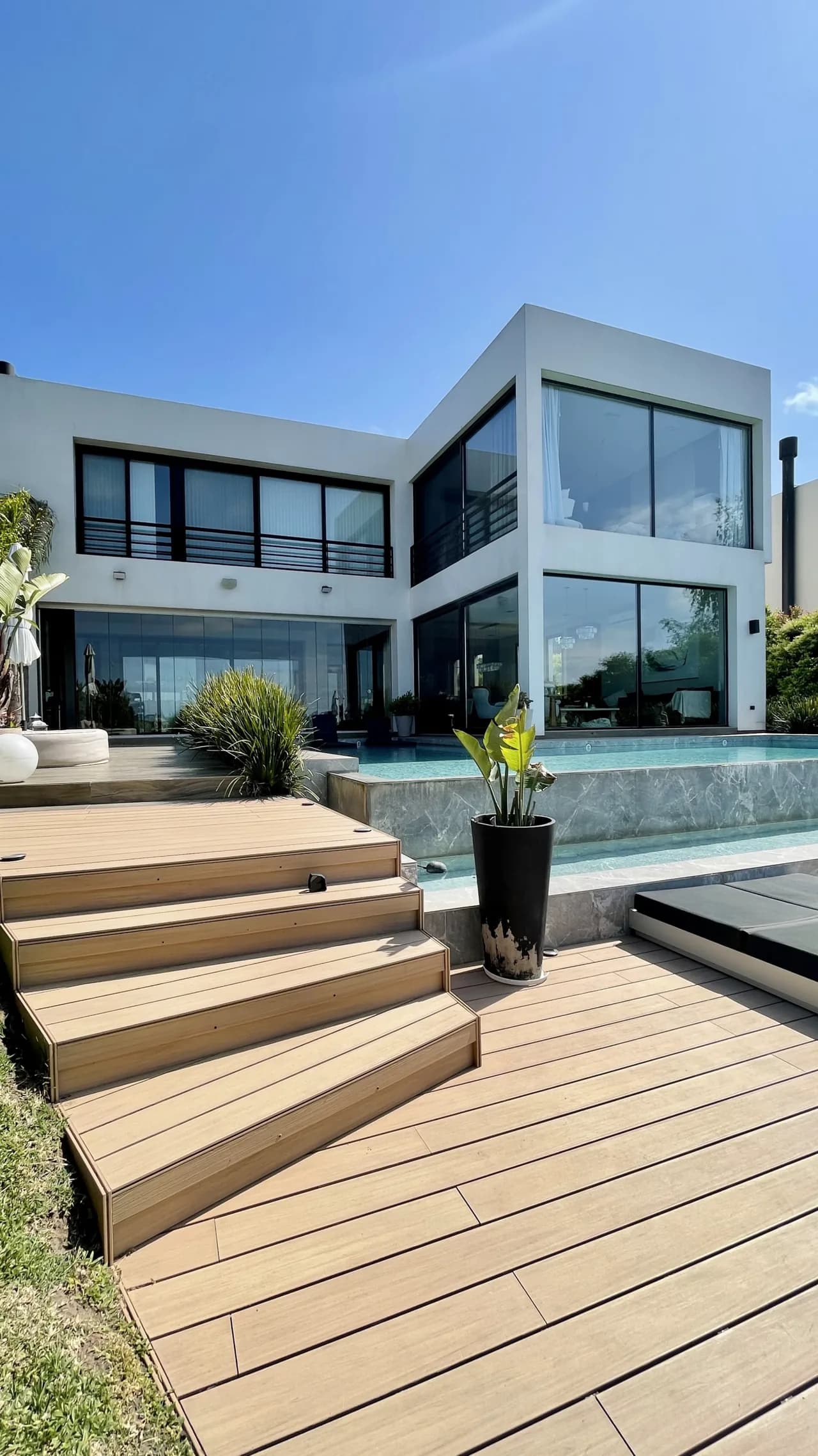Modern two-story house with WPC deck steps leading up to the pool