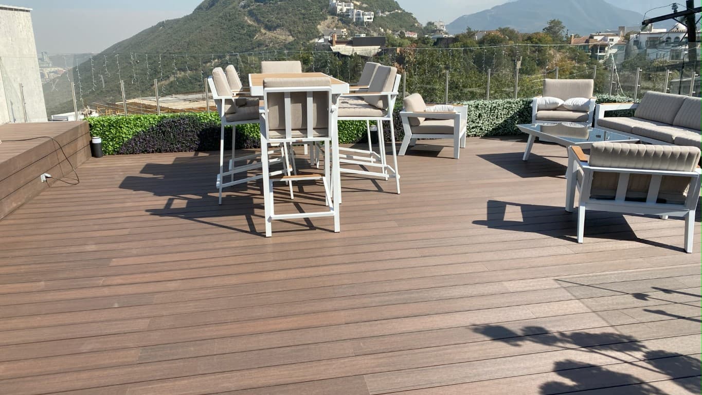 Terrace with outdoor dining on WPC decking and hills in the background