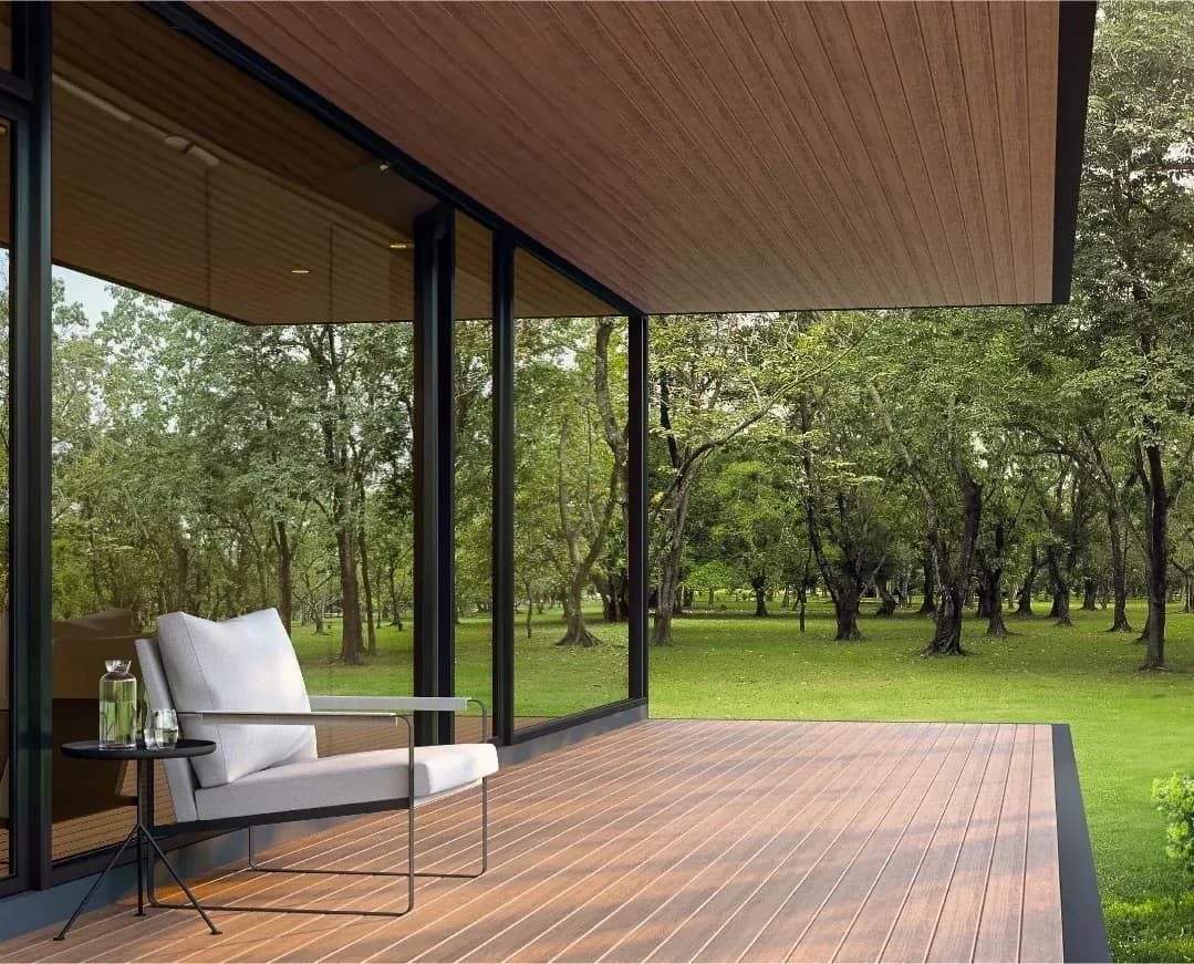 Covered terrace with WPC decking and an outdoor armchair facing a wooded garden