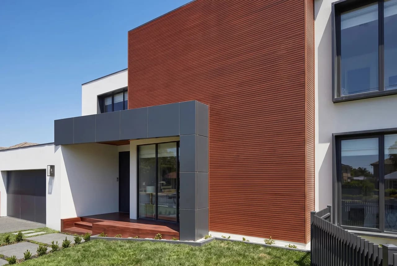 Facade with a section clad in reddish WPC grooved panel, seen from the garden