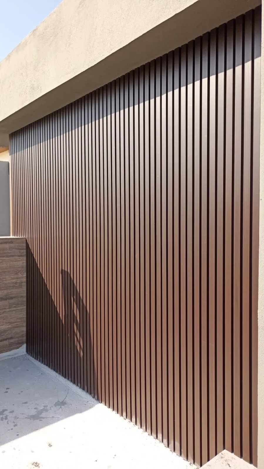 Muro alto revestido con lambrín WPC vertical tono madera