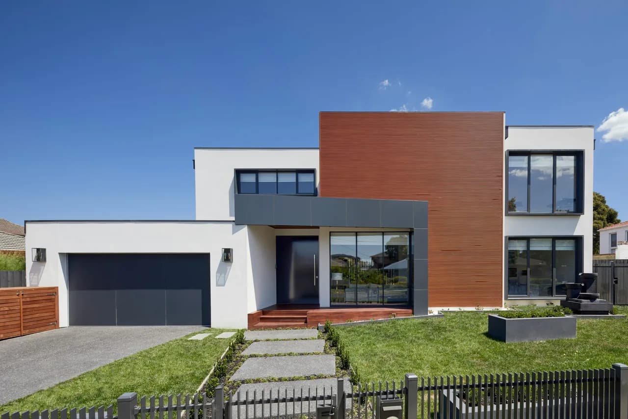 White two-story house with a reddish WPC grooved panel section over the entrance