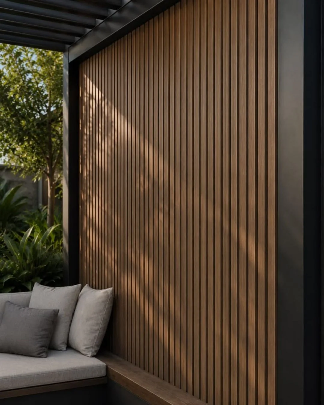 Muro exterior revestido de panel WPC ranurado tono madera junto a una sala bajo una pérgola, con plantas al fondo