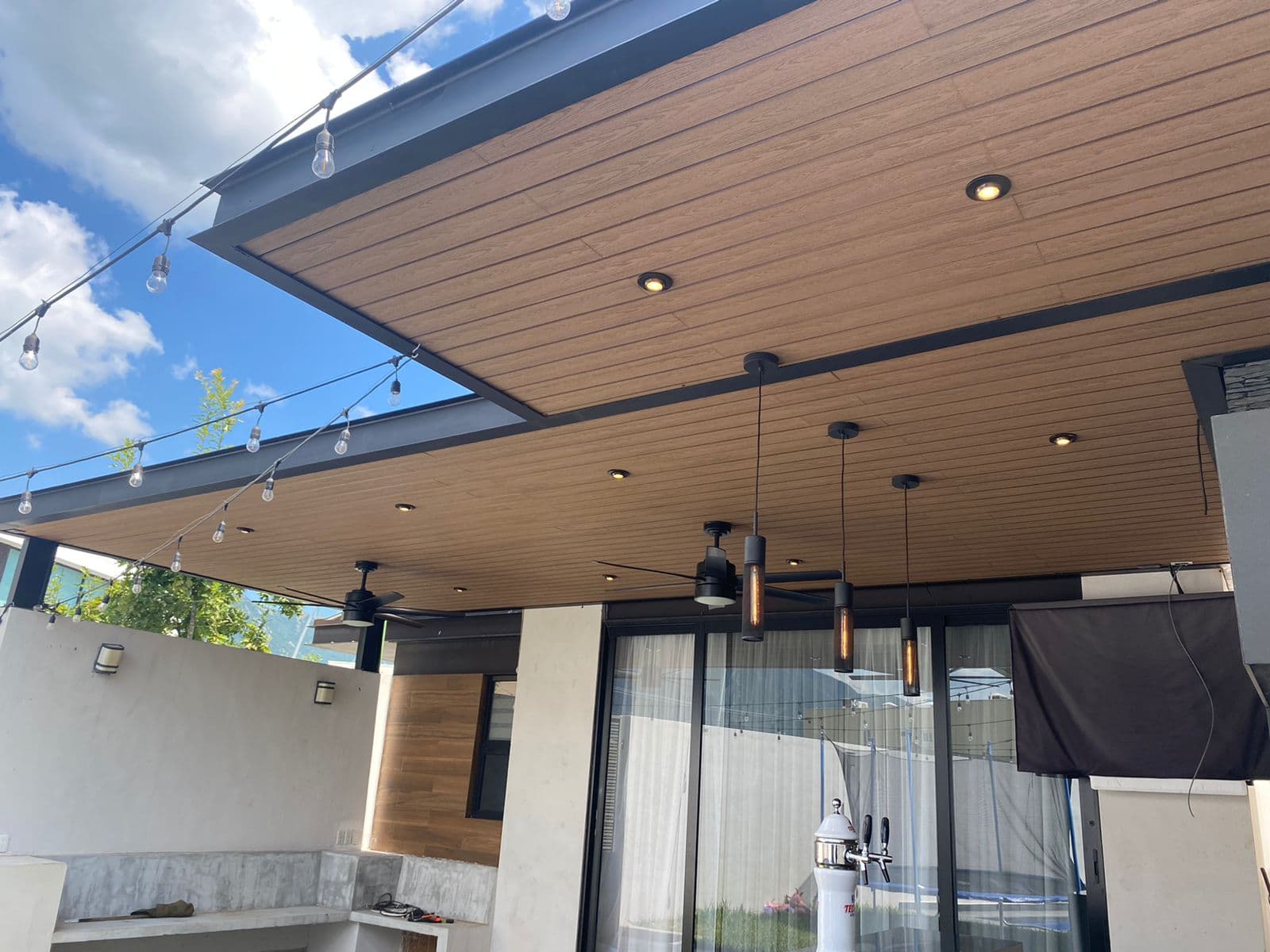 Covered patio with a wood-tone WPC cladding ceiling, pendant lights and recessed lights