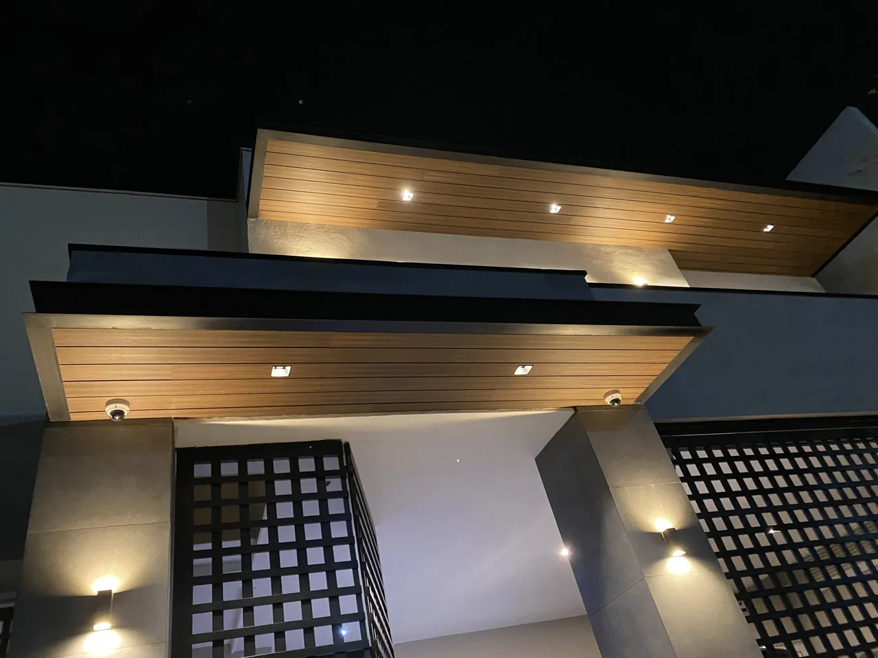 Modern facade at night, with lit WPC soffits under its overhangs