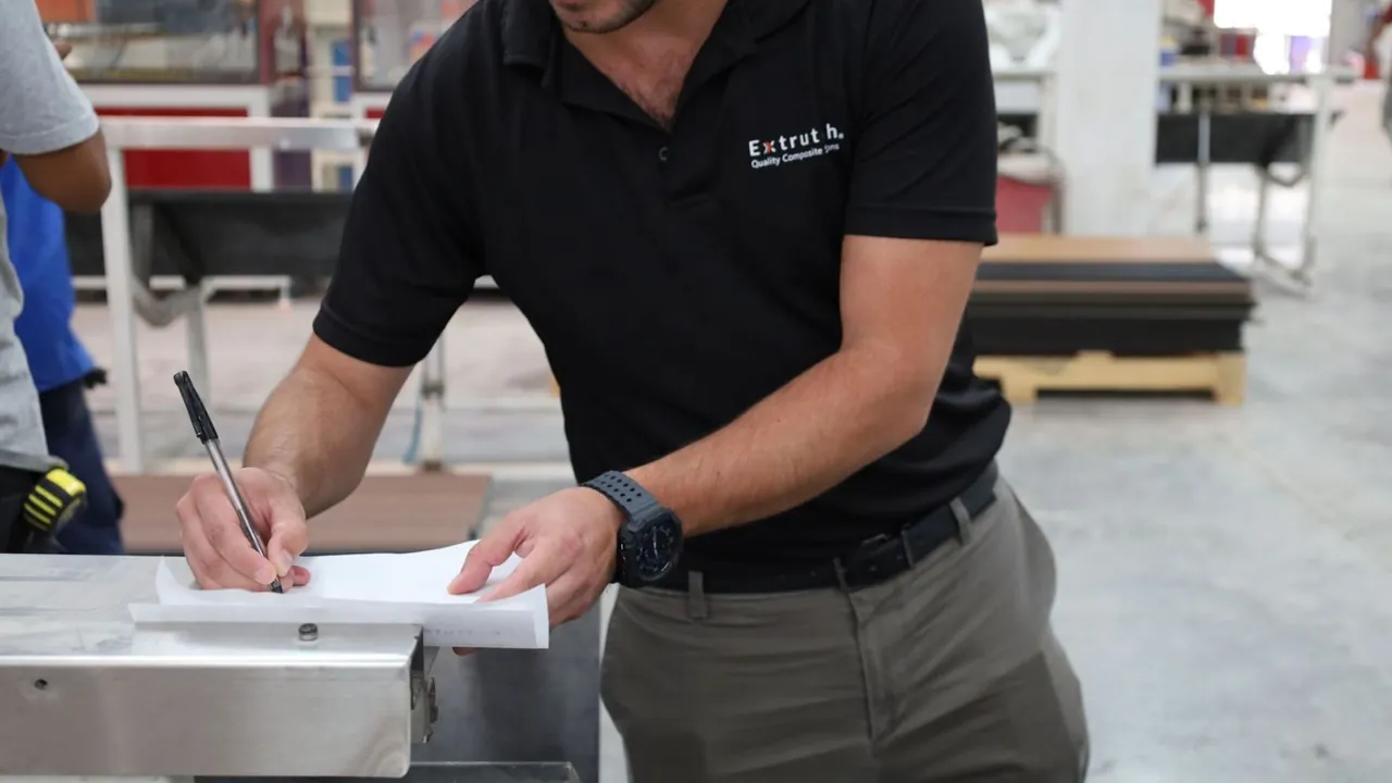 Personal de Extrutech llena un registro en la planta, junto a las tablas de WPC recién fabricadas