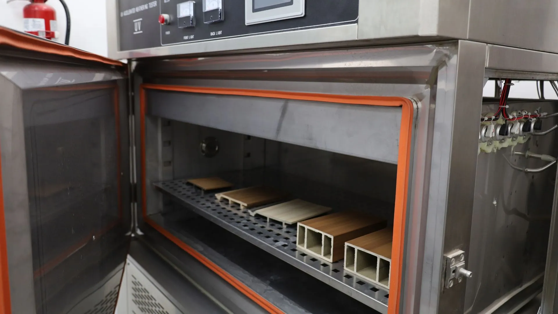 Máquina de intemperismo acelerado del laboratorio de Extrutech, abierta, con muestras de perfiles WPC en su charola