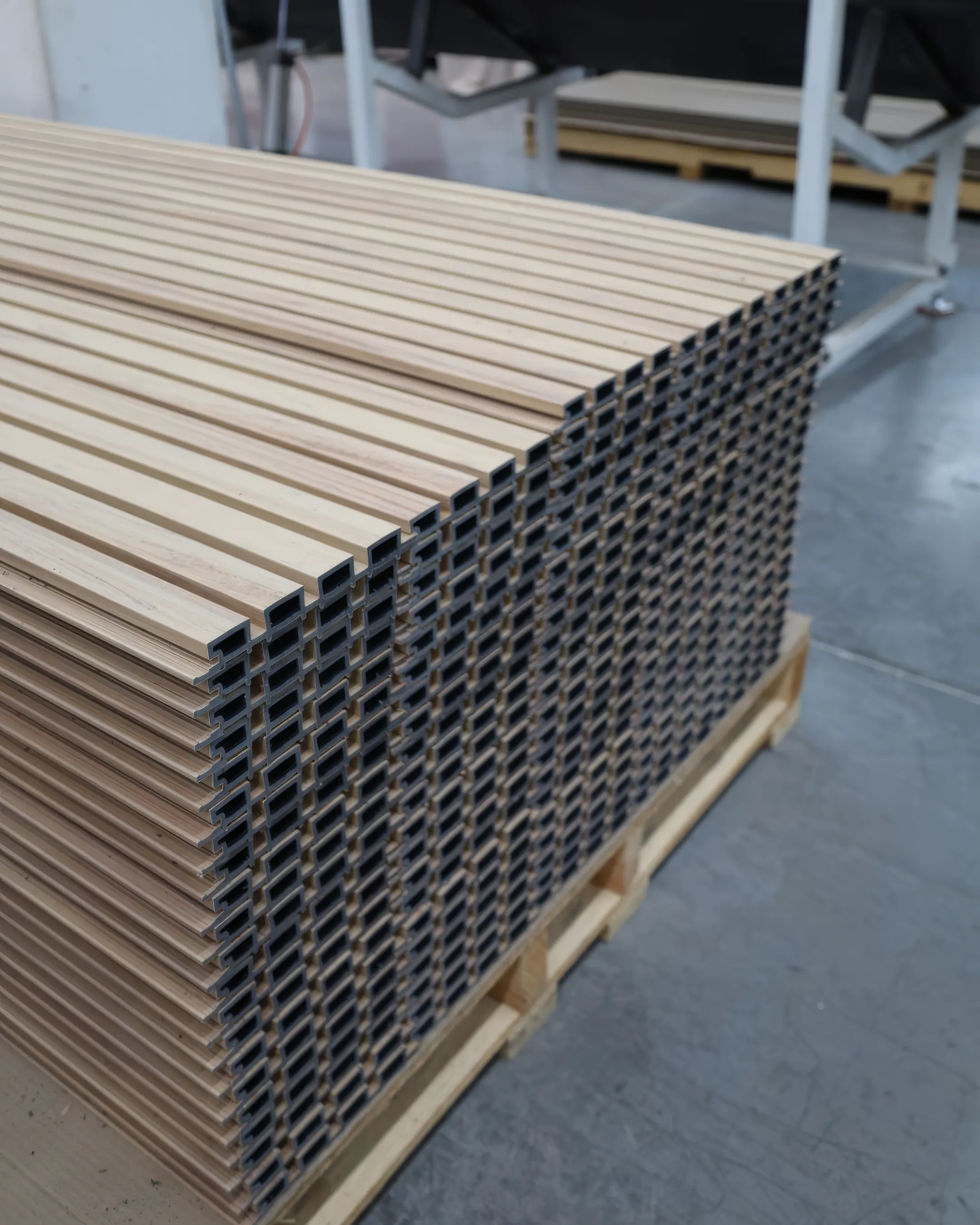 Perfiles de WPC recién fabricados estibados en una tarima en la planta de Extrutech, vistos de canto con sus cámaras huecas