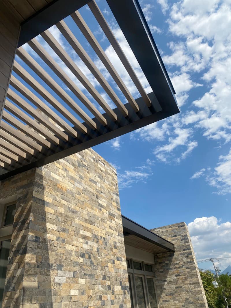 WPC beams under a facade overhang, seen from below against a blue sky
