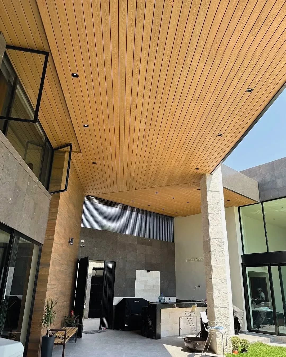 Covered patio of a house with a WPC board ceiling and stone columns