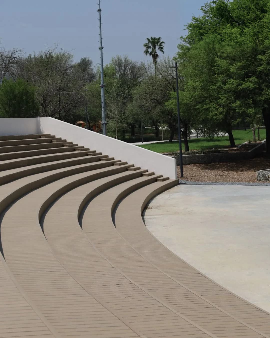 Graderío curvo de una plaza pública recubierto con deck de WPC color arena
