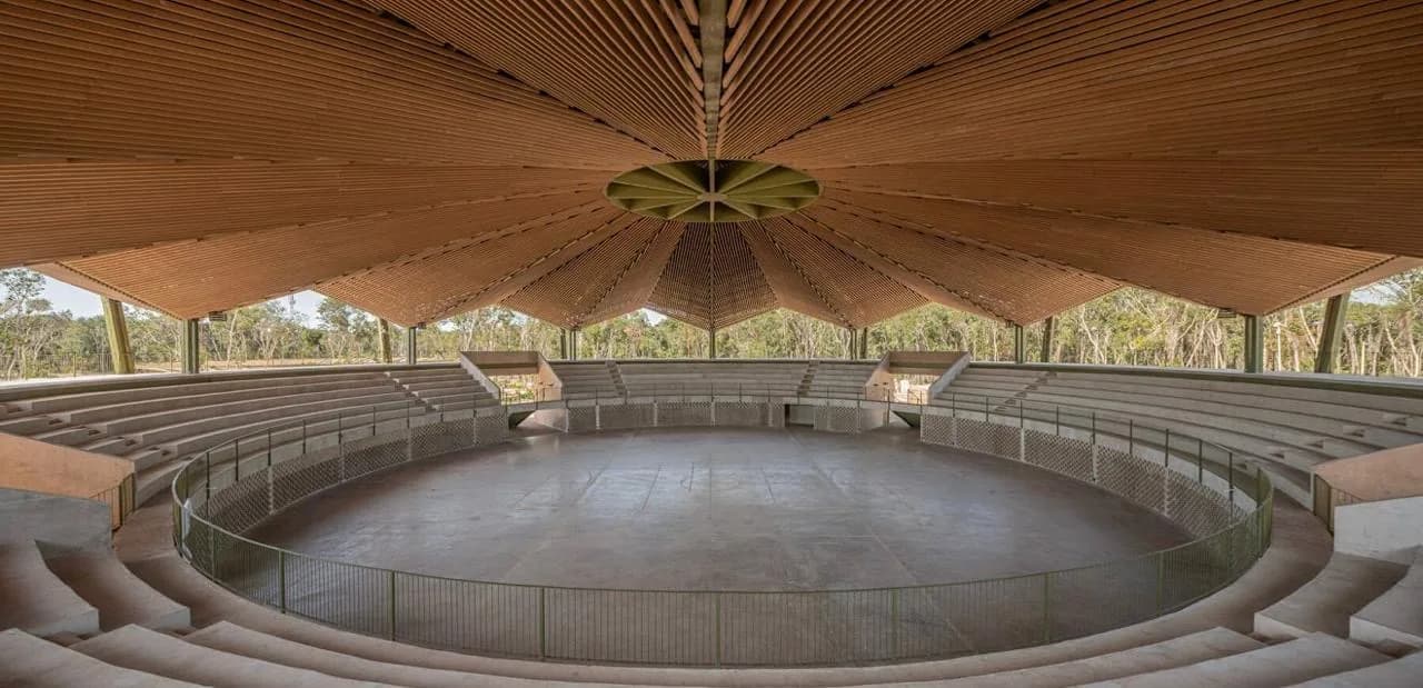 Foro circular al aire libre del Parque Quintana Roo, con gradas de piedra bajo un gran techo en abanico de vigas de WPC en tono madera