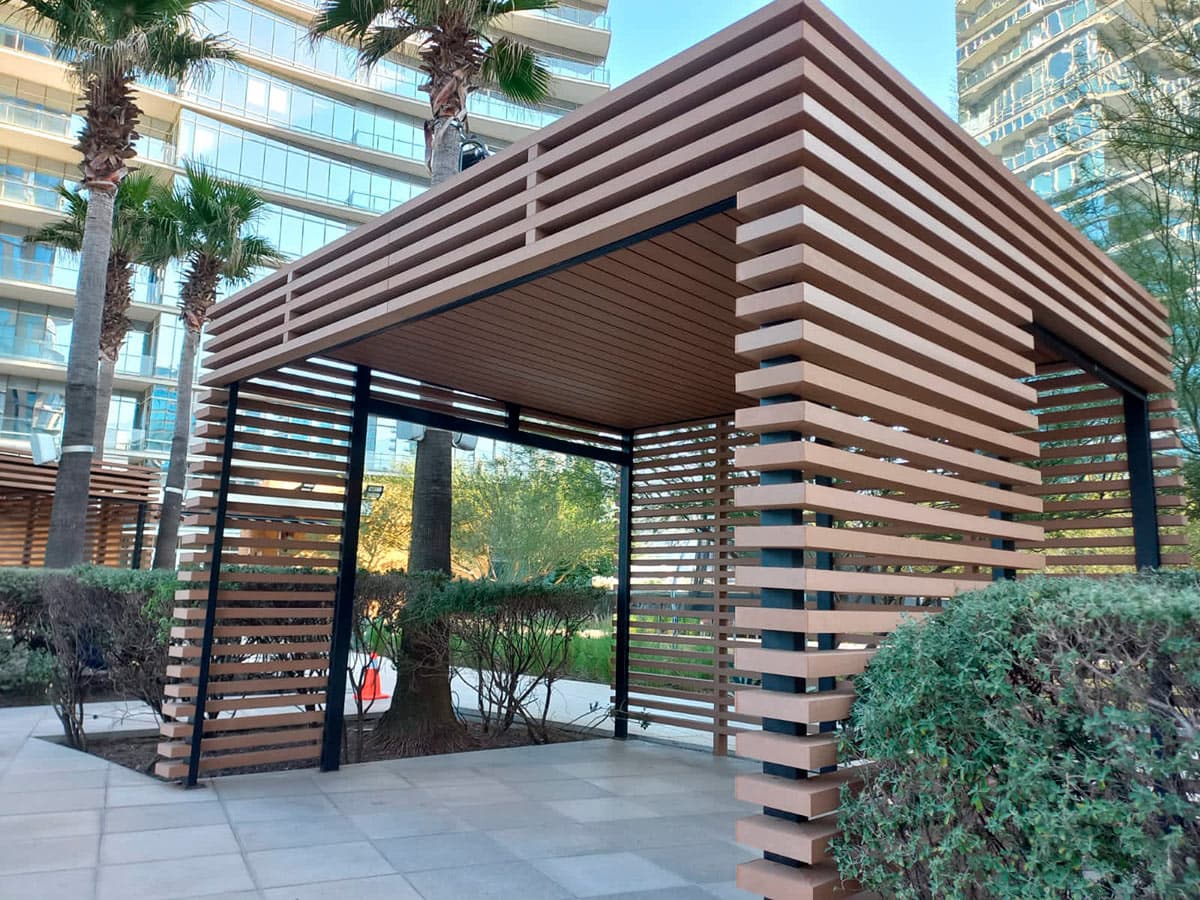 Pavilion of horizontal WPC beams in a plaza, with buildings in the background
