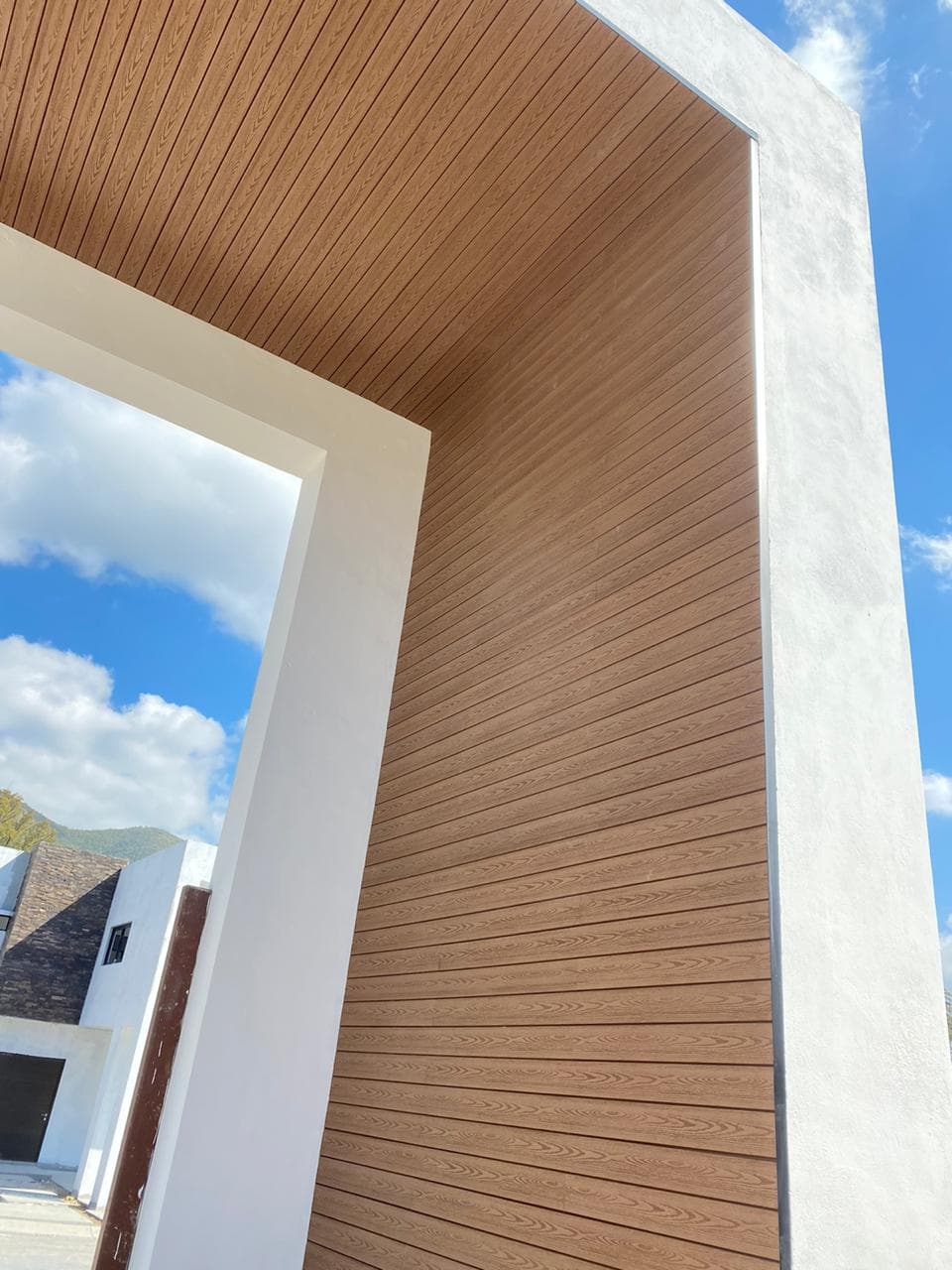 Corner of a house with the wall and eaves clad in wood-tone WPC Wall Cladding
