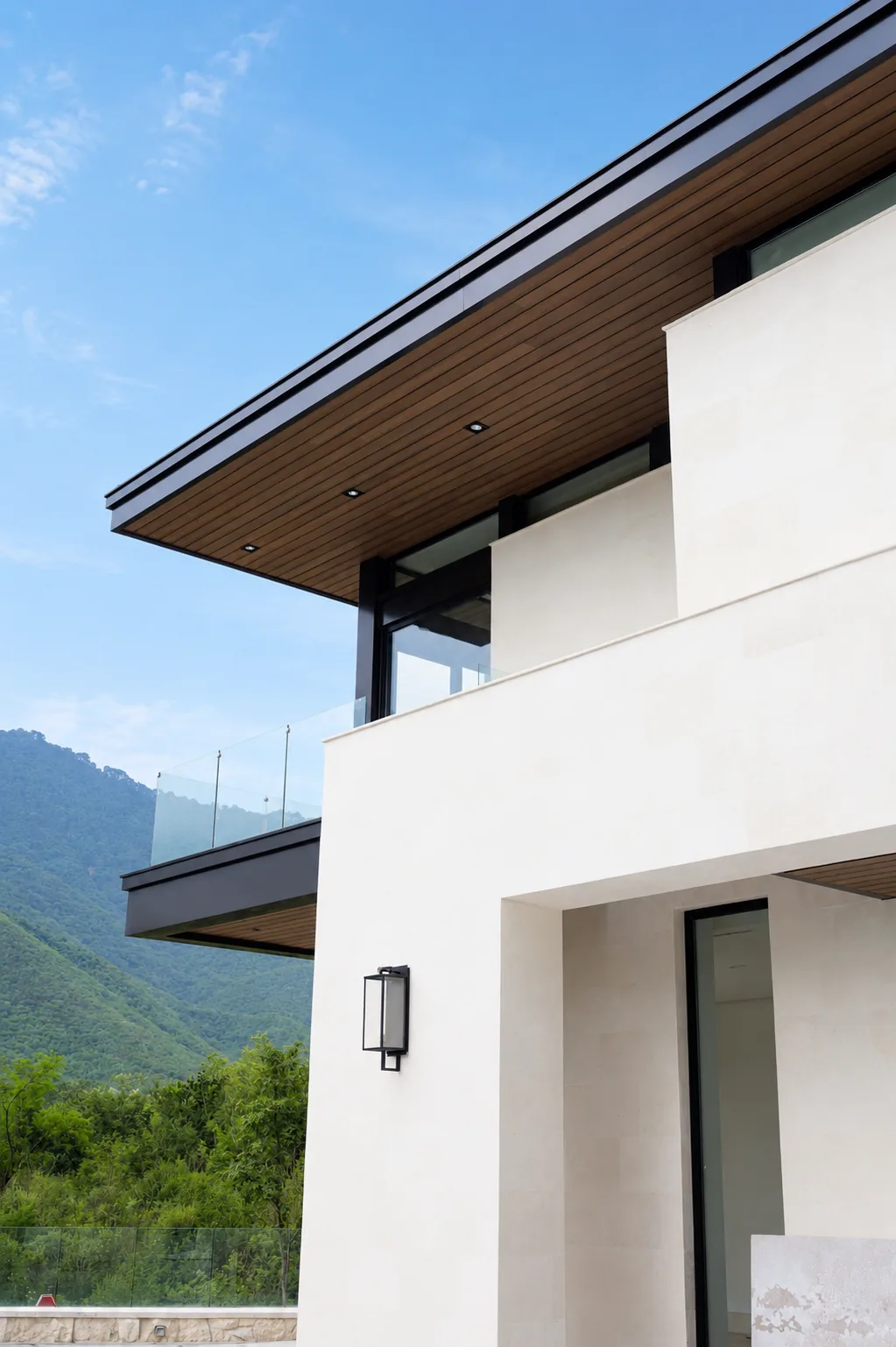 Volado de una casa blanca revestido por debajo de Wall Cladding WPC tono madera, con los cerros al fondo