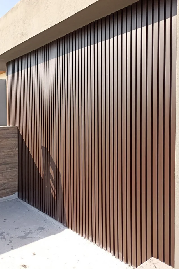 Vertical wood-tone WPC grooved panel wall with afternoon shadows