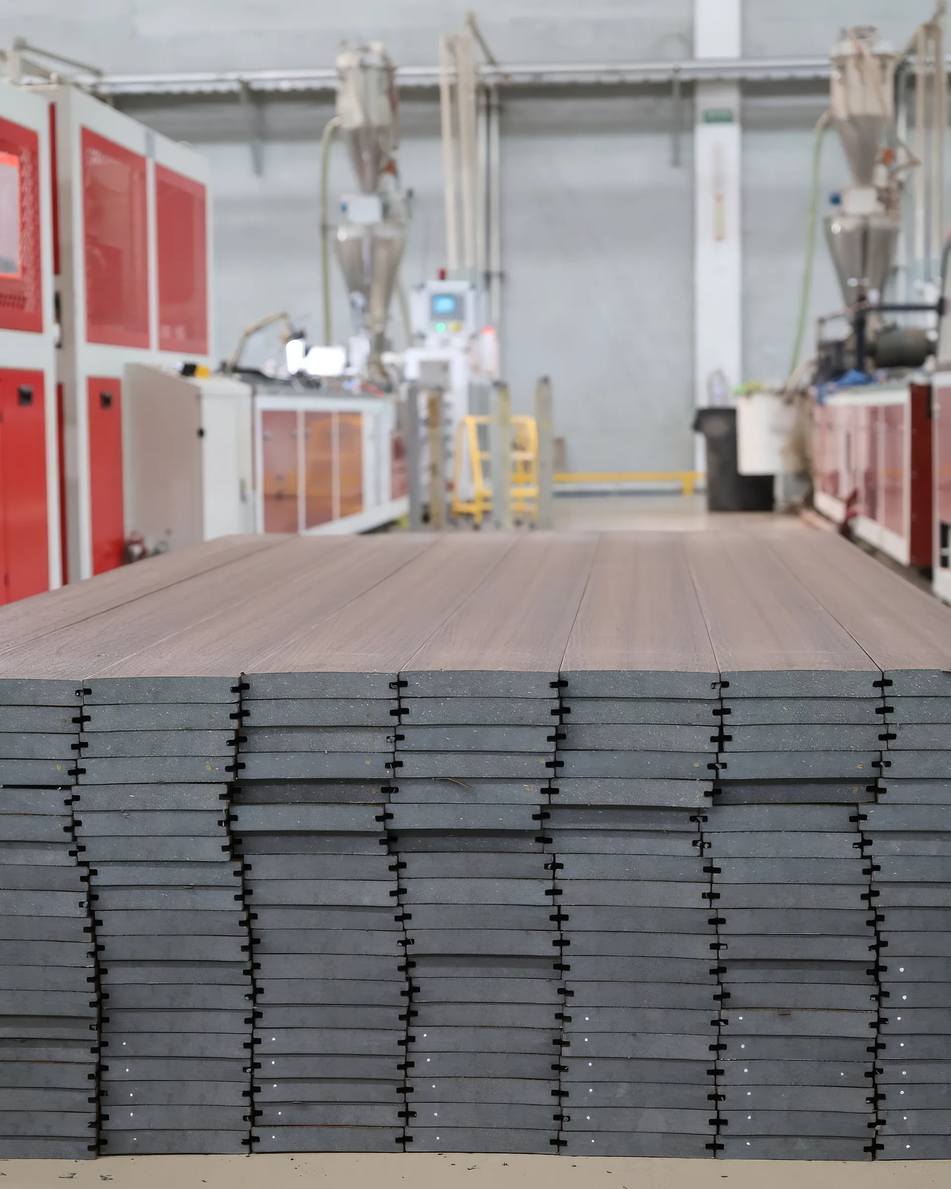 Estiba de tablas de deck WPC al final de la línea de producción de Extrutech, vistas de canto, listas para embarque