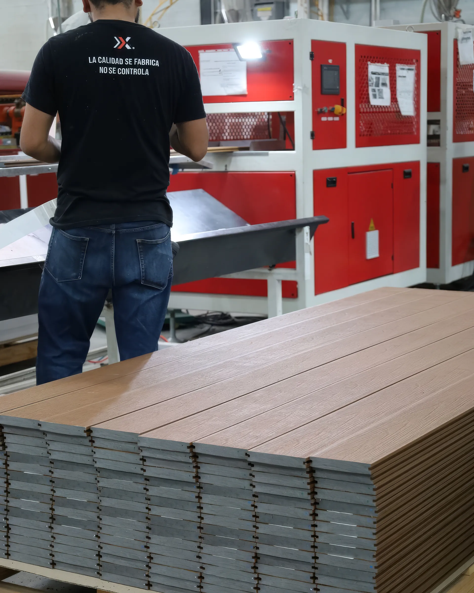 Un operador de Extrutech junto a la estiba de tablas de deck WPC en la planta