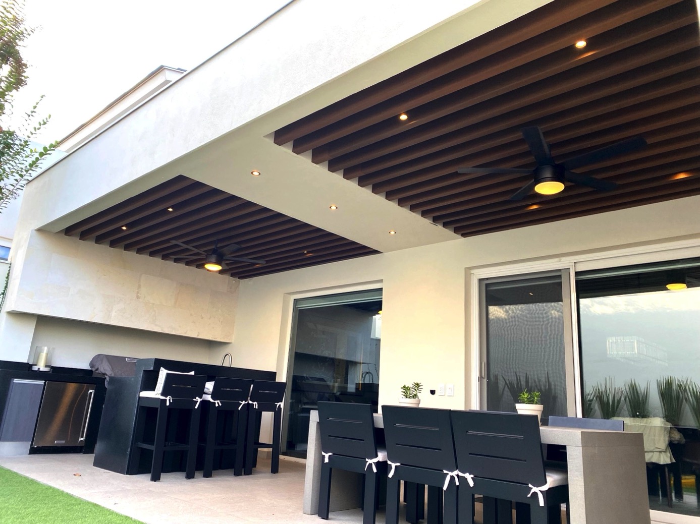 Pérgola de Vigas Decorativas sobre la terraza de una casa, con el comedor de exterior debajo